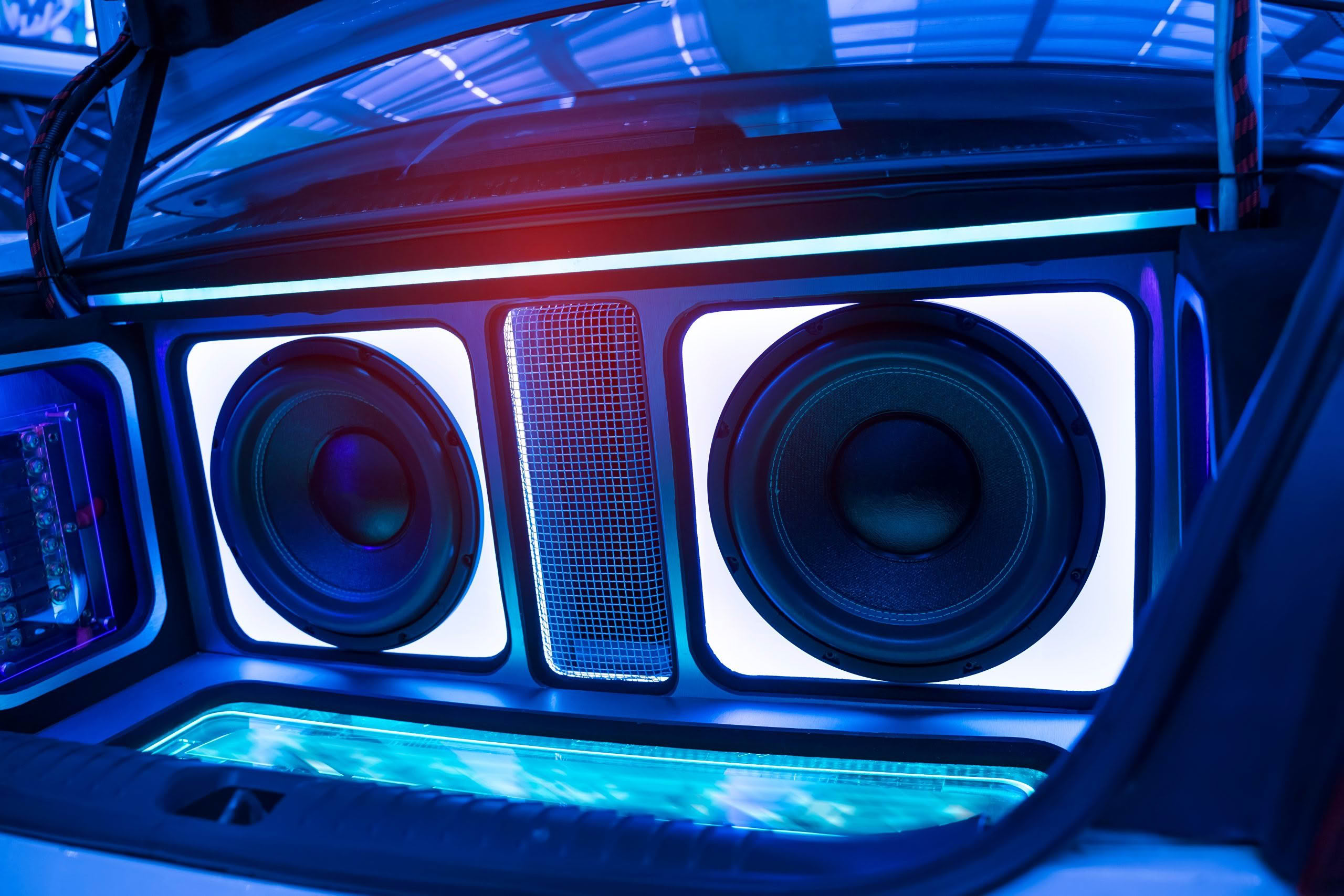 Car trunk with illuminated subwoofers and speakers.