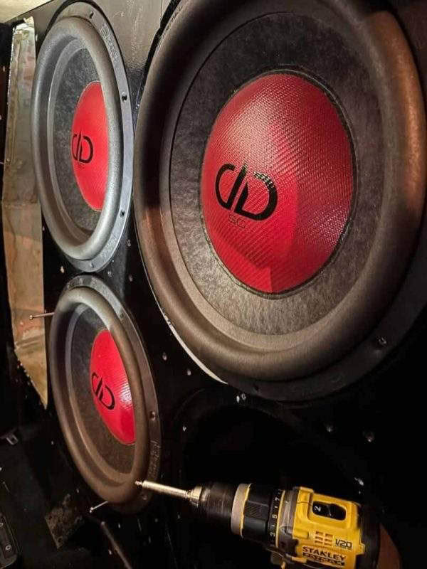 Car subwoofers being installed with power drill